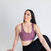 Woman showing front of purple nursing sports bra from Joyleta (maternity store in Canada).