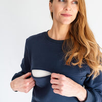 Woman showing nursing zipper opening on midnight blue zipper breastfeeding sweatshirt.