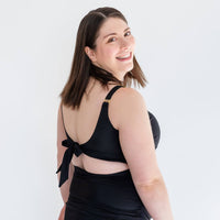Pregnant woman showing back of black maternity bathing suit from Joyleta, a Canadian maternity activewear company.