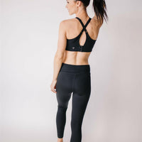 Woman wearing black maternity leggings and nursing sports bra.
