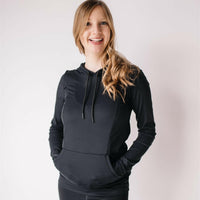 Woman showing front of black nursing hoodie from Joyleta, a maternity activewear store in Canada.