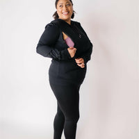Woman showing zipper openings on black nursing hoodie from maternity store in Canada (Joyleta).