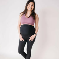 Woman wearing black maternity leggings and nursing sports bra.