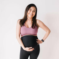 Woman wearing black maternity leggings and nursing sports bra.