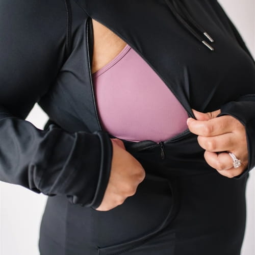 Woman wearing black nursing hoodie from Canadian maternity store, Joyleta, with zipper unzipped.