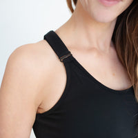 Woman showing closeup of black adjustable strappy back sports bra.