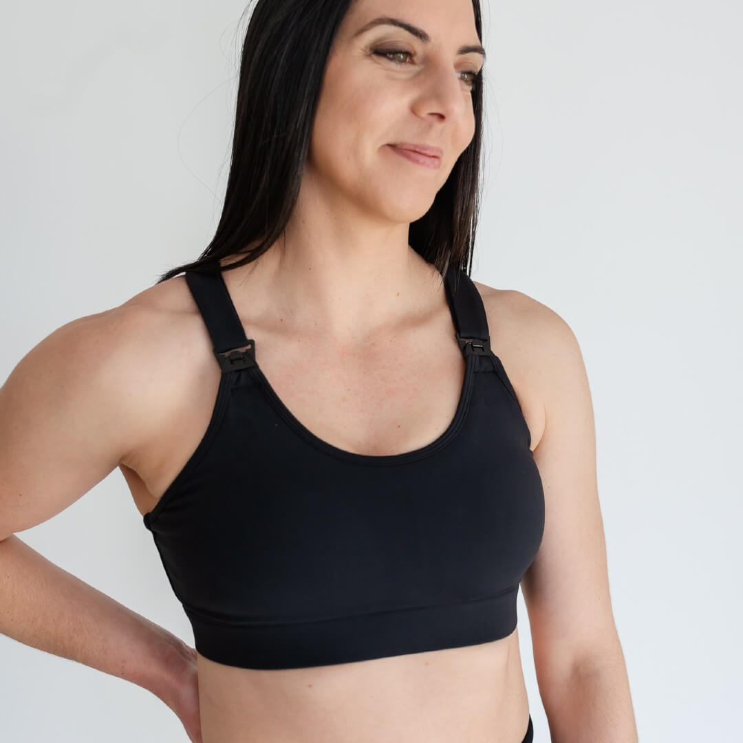 Woman showing front of strappy-back black nursing sports bra from Joyleta Canada.