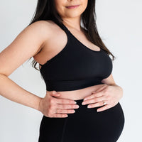 Pregnant woman wearing black maternity sports bra from Joyleta (maternity store in Canada).