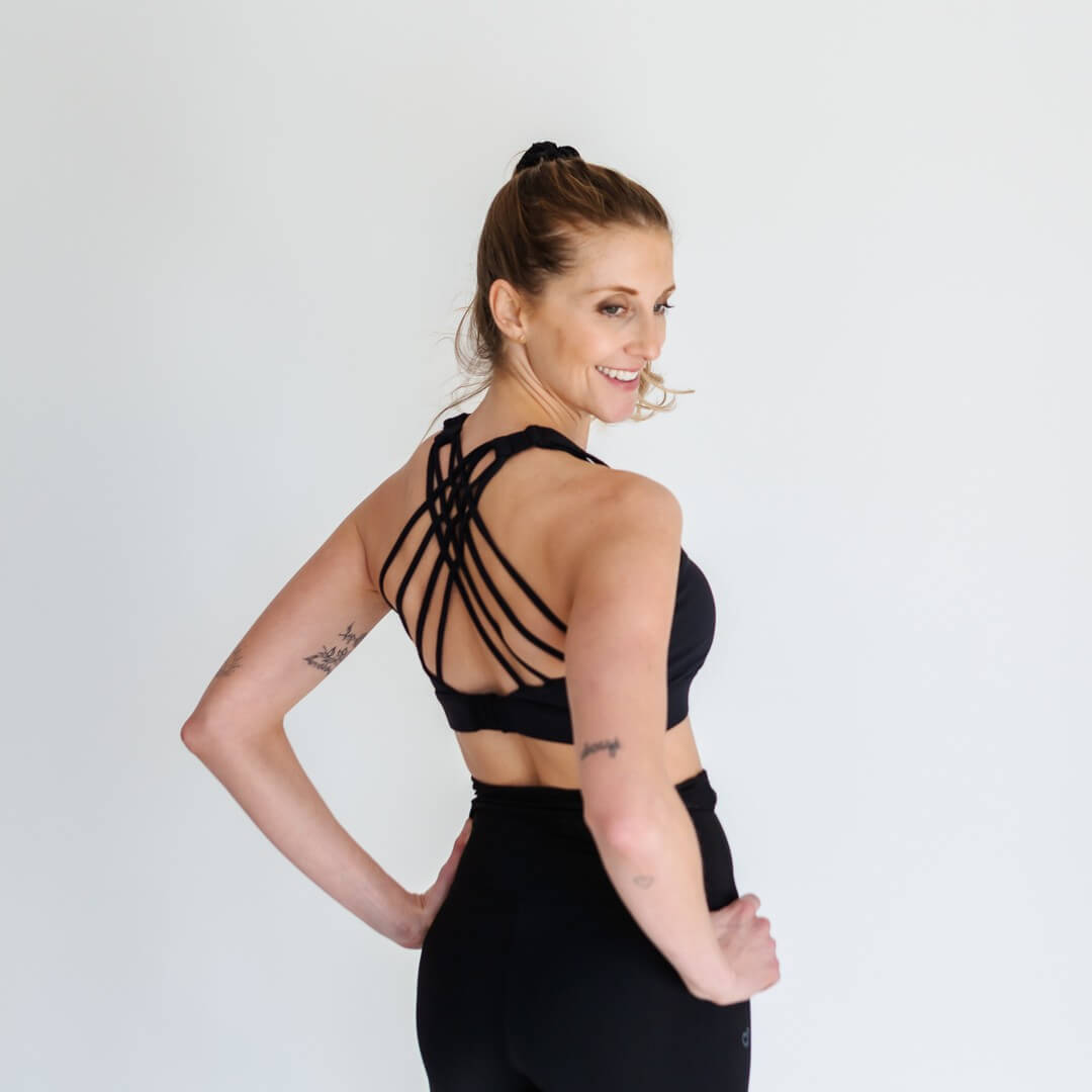 Woman showing strappy back of black adjustable sports bra from Joyleta Canada.