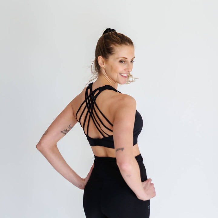 Woman showing strappy-back of black nursing sports bra from Joyleta Canada.