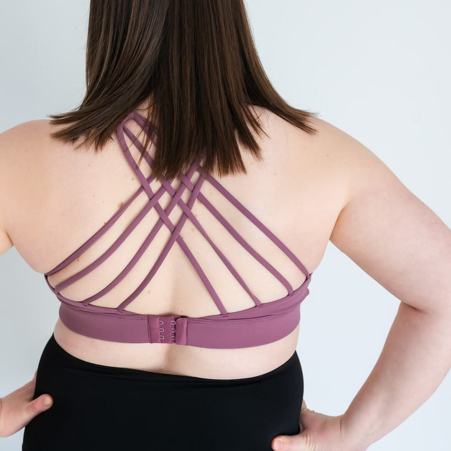 Woman showing strappy-back of purple nursing sports bra from Canadian maternity store, Joyleta.