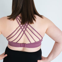 Woman showing back of purple strappy-back sports bra from Joyleta Canada.