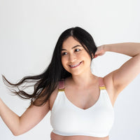 Woman flipping hair and wearing white nursing sports bra with gold nursing clasps and pink straps from Joyleta, a maternity activewear store in Canada.