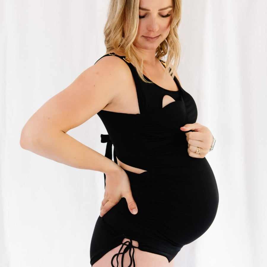 Woman wearing black maternity swimsuit with drop-down nursing clips as a nursing tankini