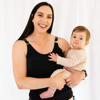 Woman wearing black maternity and nursing swimsuit and holding baby