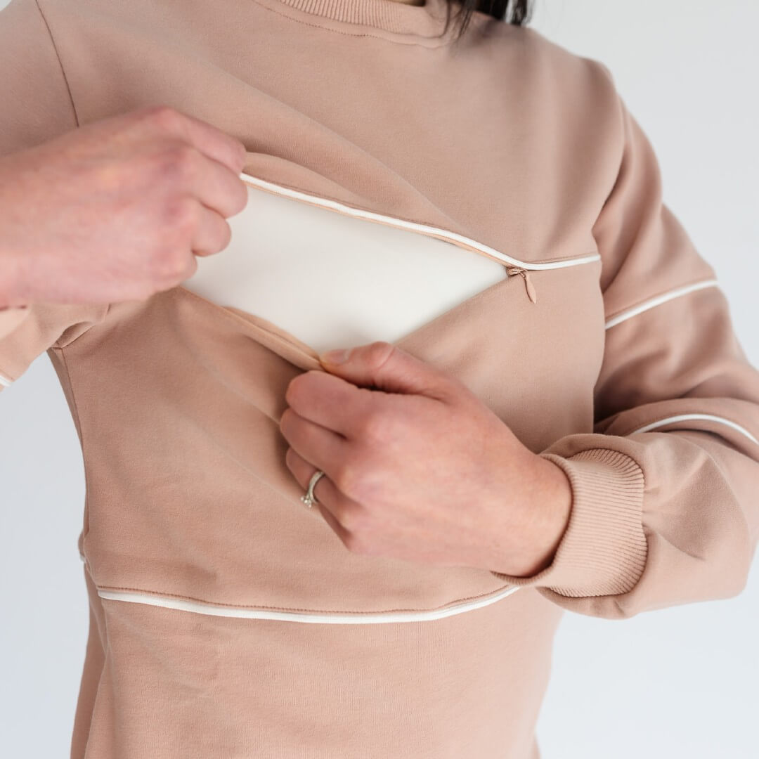 Woman showing invisible horizontal zipper openings on Pinktaupe warm breastfeeding sweatshirt.