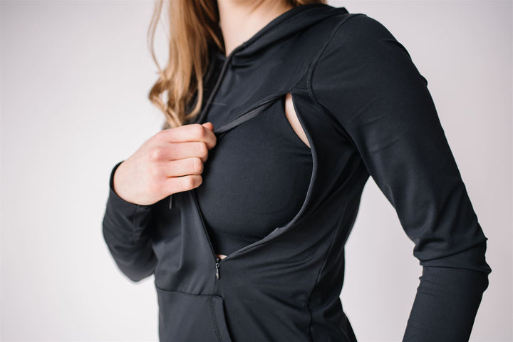 Woman showing hidden nursing zippers on black maternity and nursing hoodie from Joyleta, a Canadian nursing and maternity activewear company.