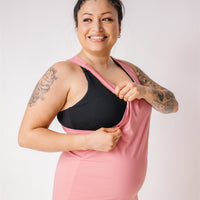 Mother showing nursing option of pink maternity tank top.