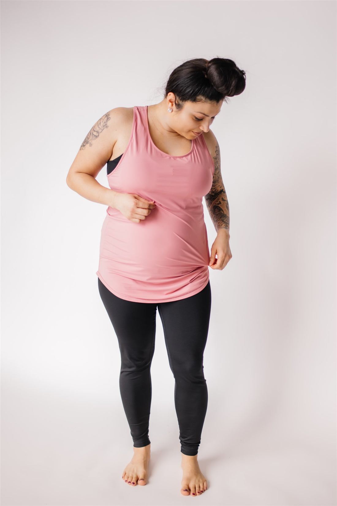 Mother wearing long maternity workout tank top in dusty rose and black maternity leggings.