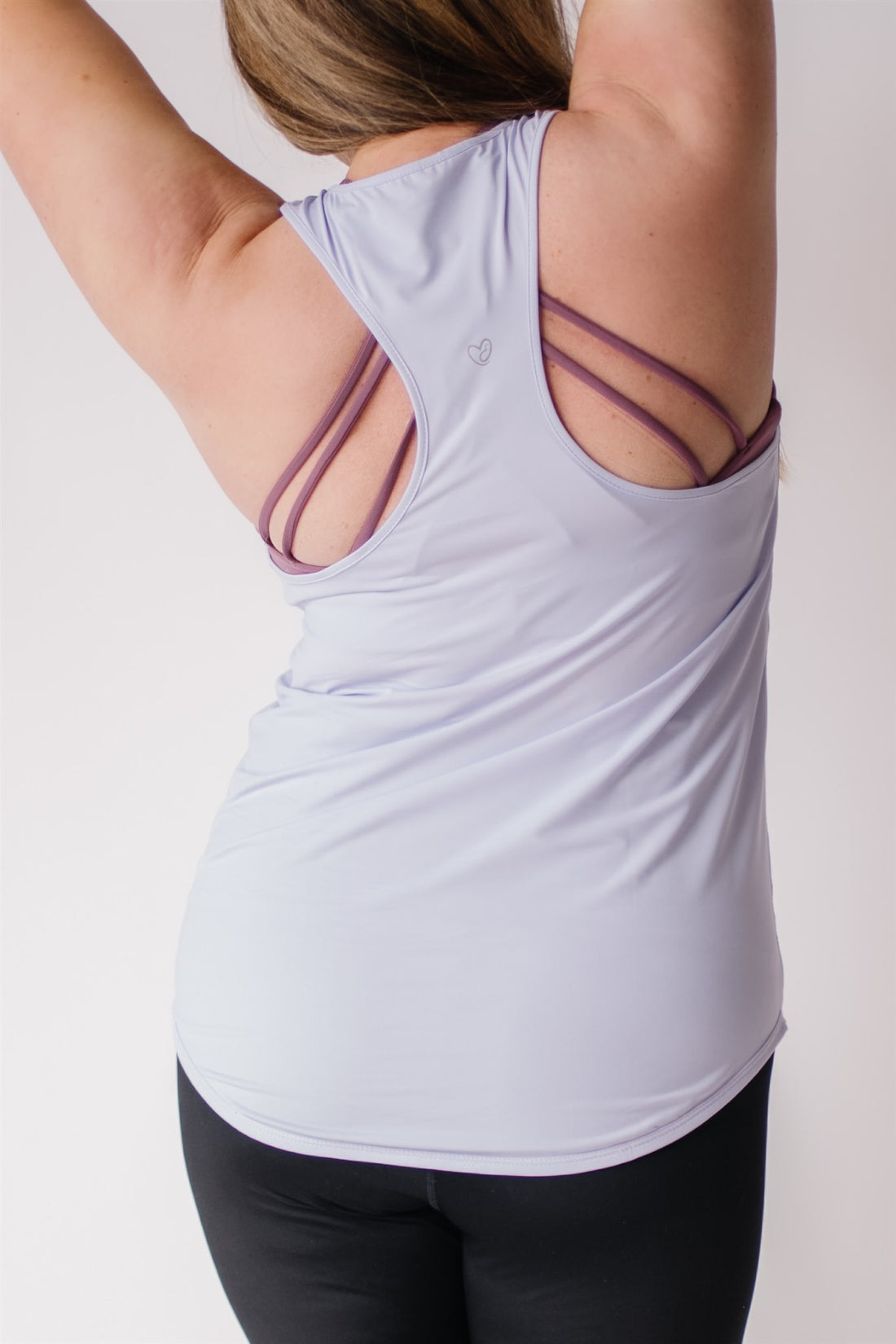 Woman showing racerback of long maternity tank top in lavender.