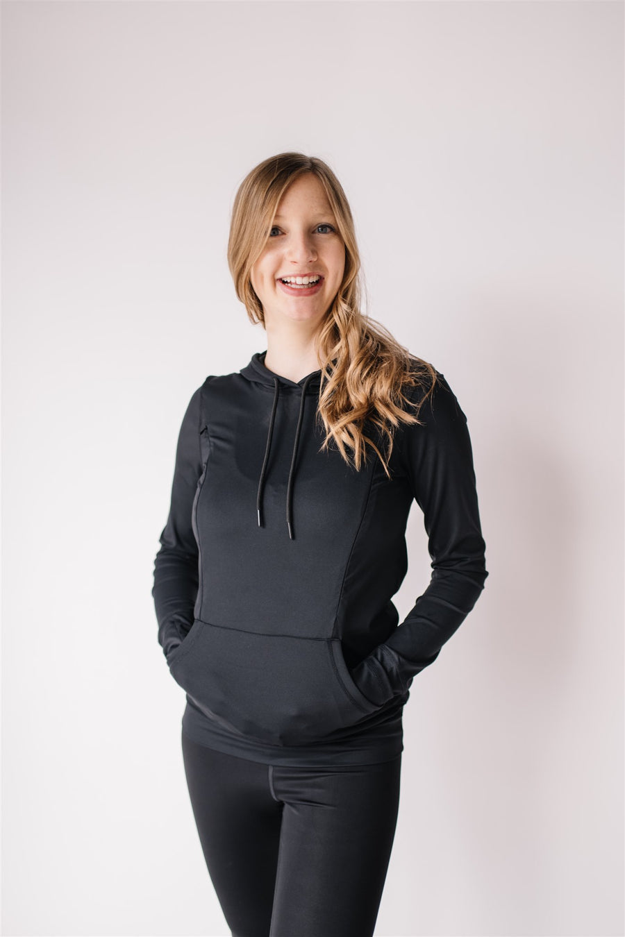 Woman showing front of black nursing hoodie from Joyleta, a maternity activewear store in Canada.