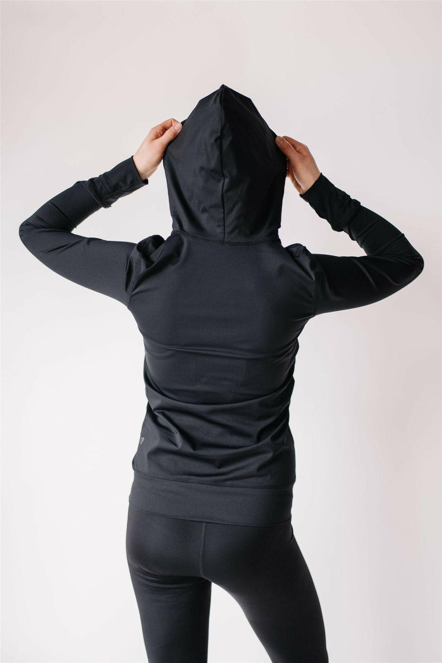 Woman showing back of black maternity leggings and black nursing hoodie from Joyleta maternity store Canada.